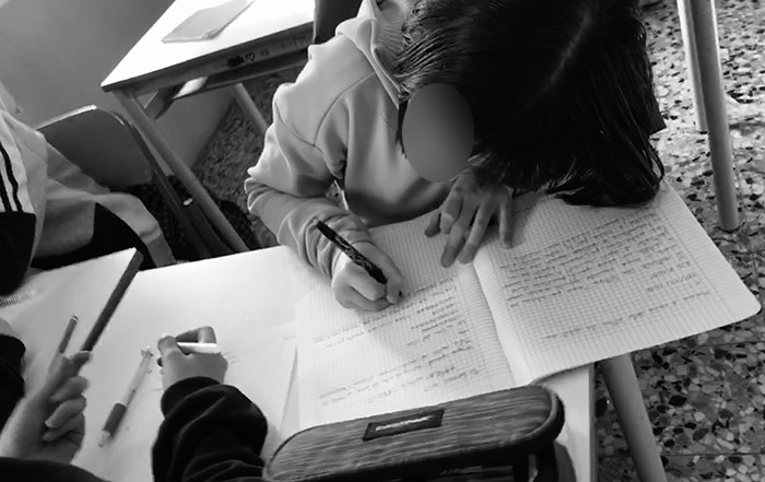 Bambino a scuola che scrive su un quaderno